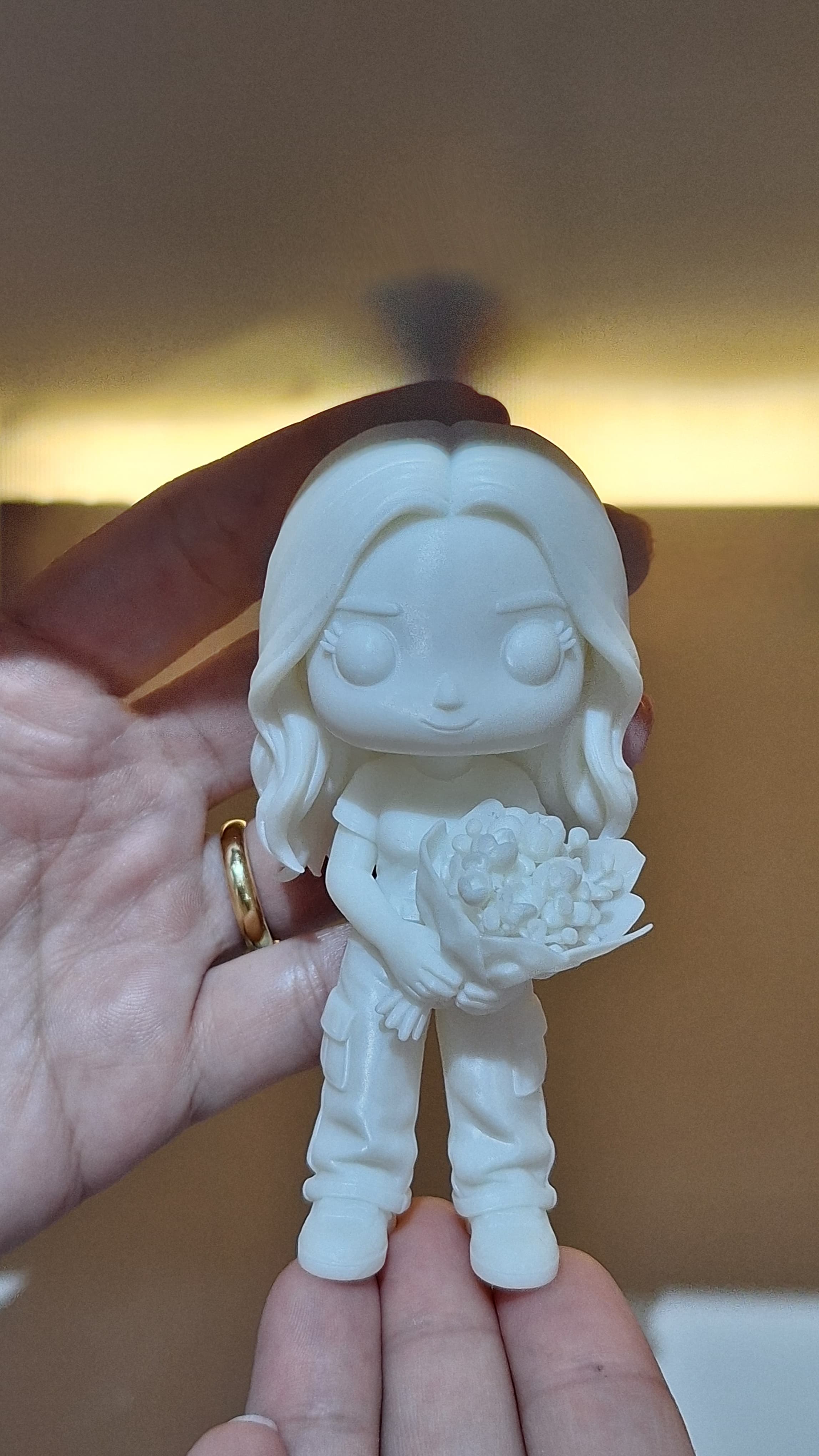 Detalhe da noiva em miniatura, em resina branca, segurada na mão