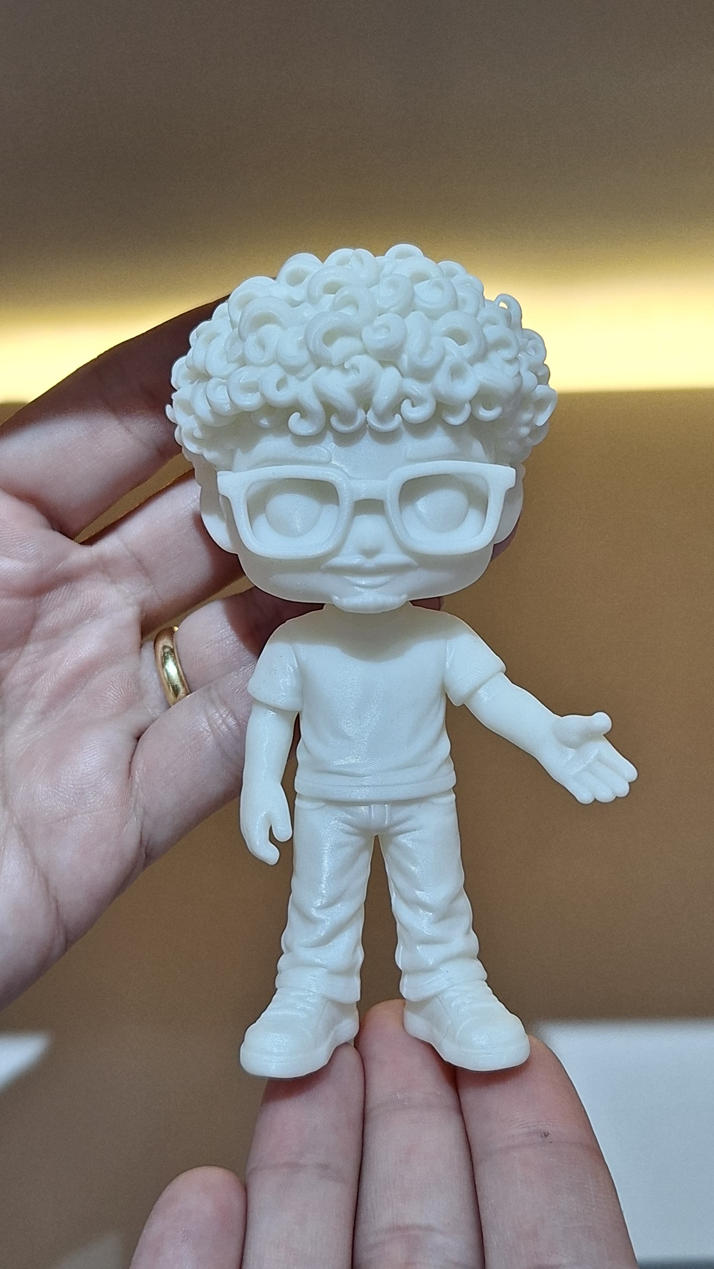 Detalhe do noivo em miniatura, em resina branca, segurado na mão