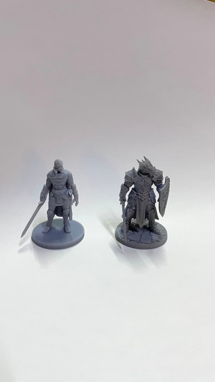 Duas miniaturas de RPG em resina cinza, sobre fundo branco