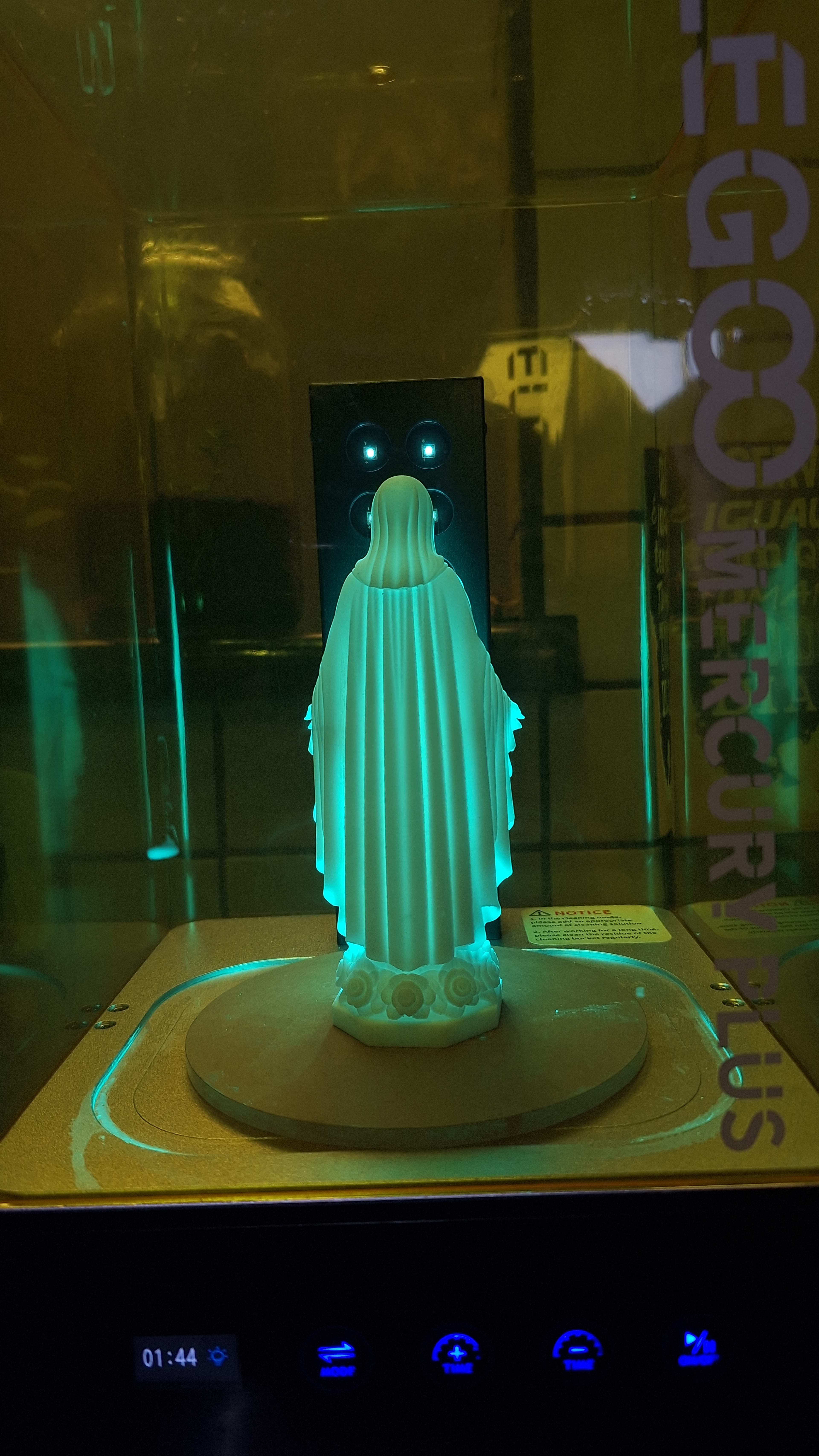 Peça dentro da câmara de cura, iluminada por luz ultravioleta verde