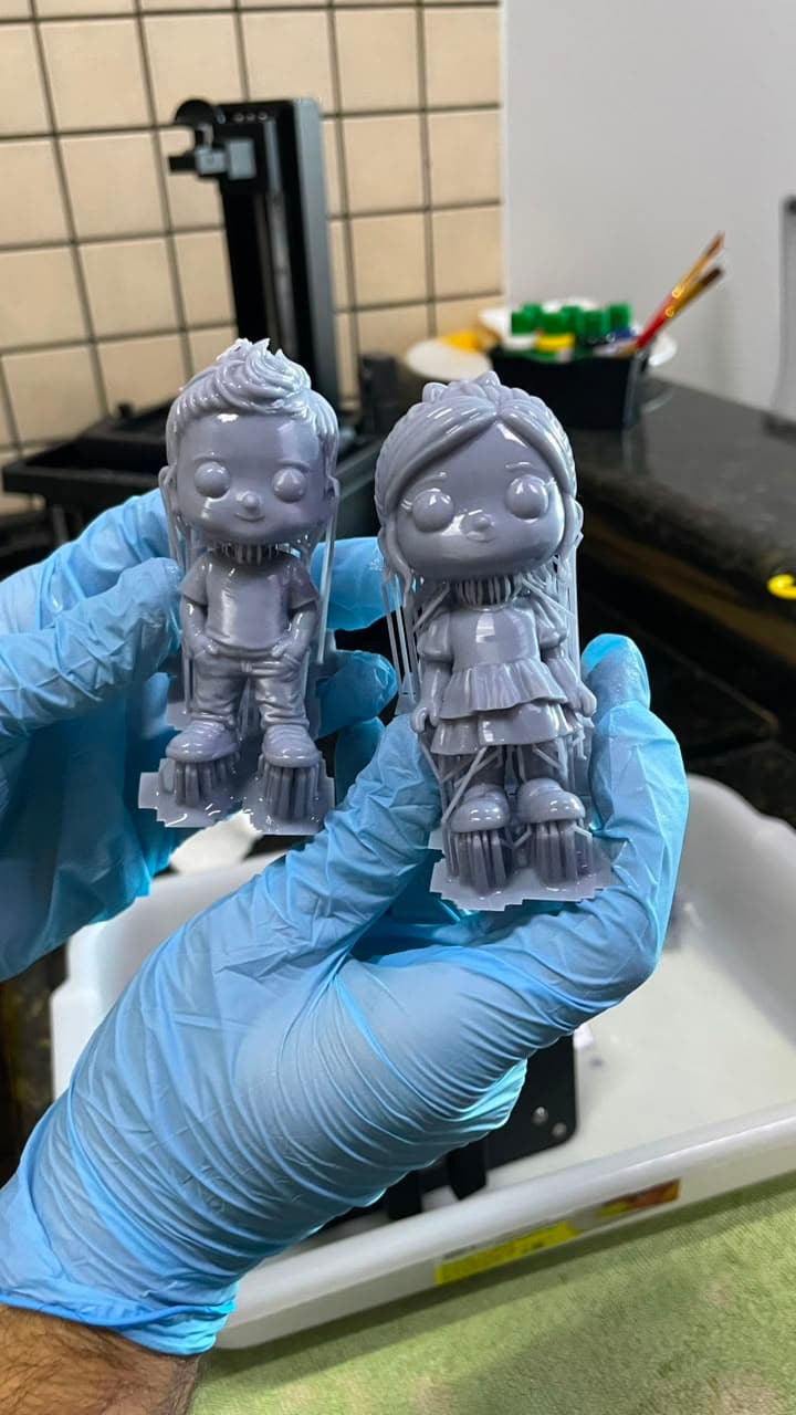 Miniaturas recém-impressas em resina cinza, ainda presas aos suportes