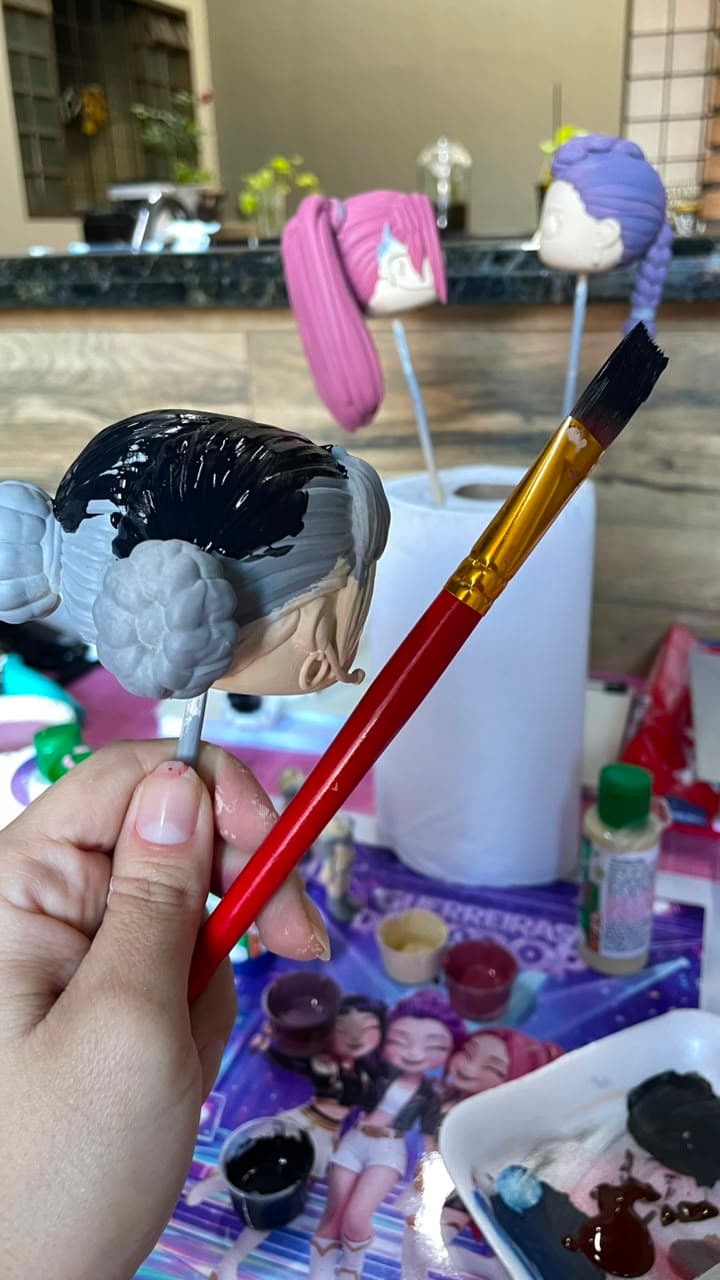 Pincel aplicando tinta em detalhe sobre a cabeça de uma miniatura