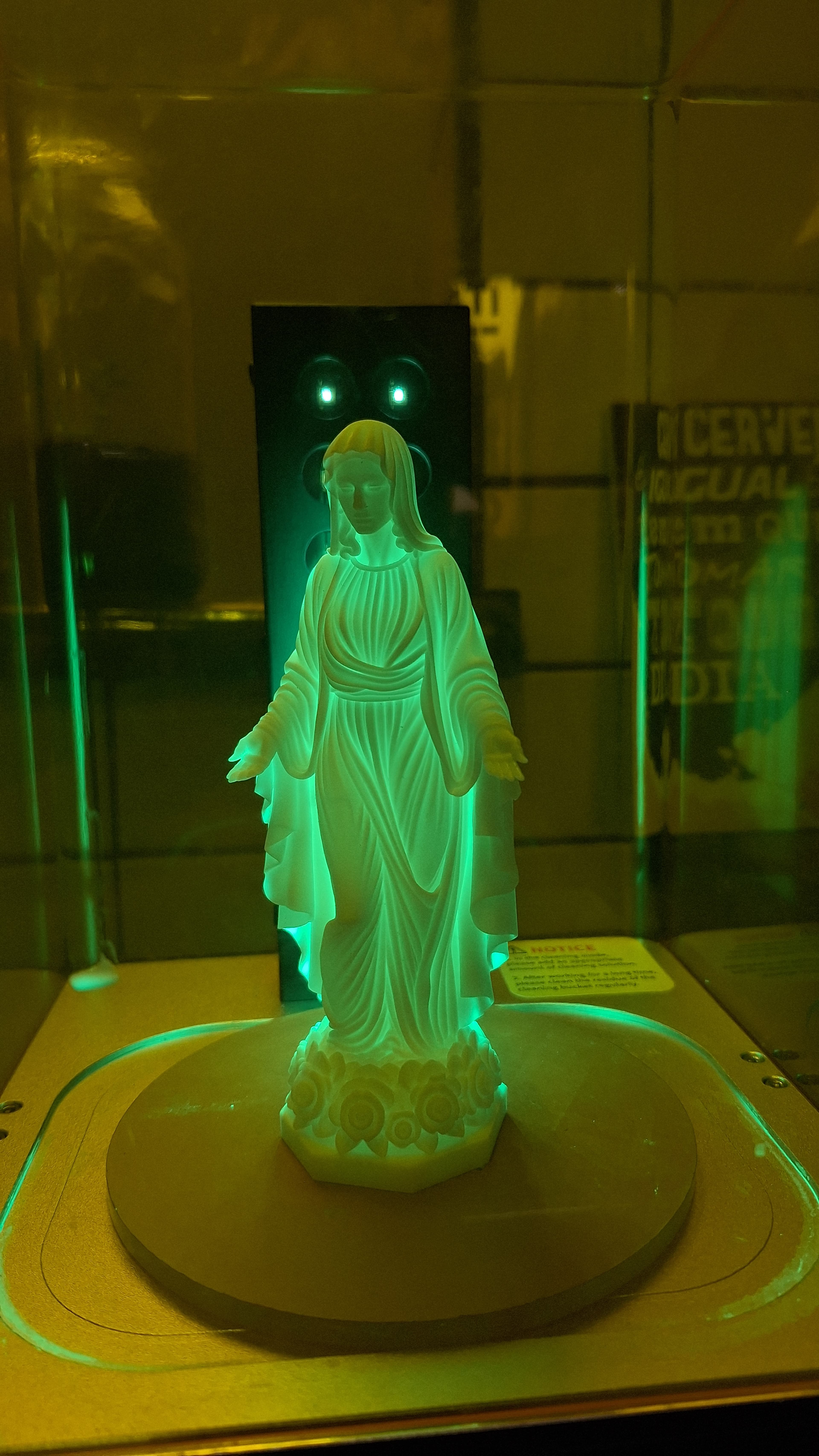 Imagem religiosa dentro da câmara de cura, iluminada por luz ultravioleta